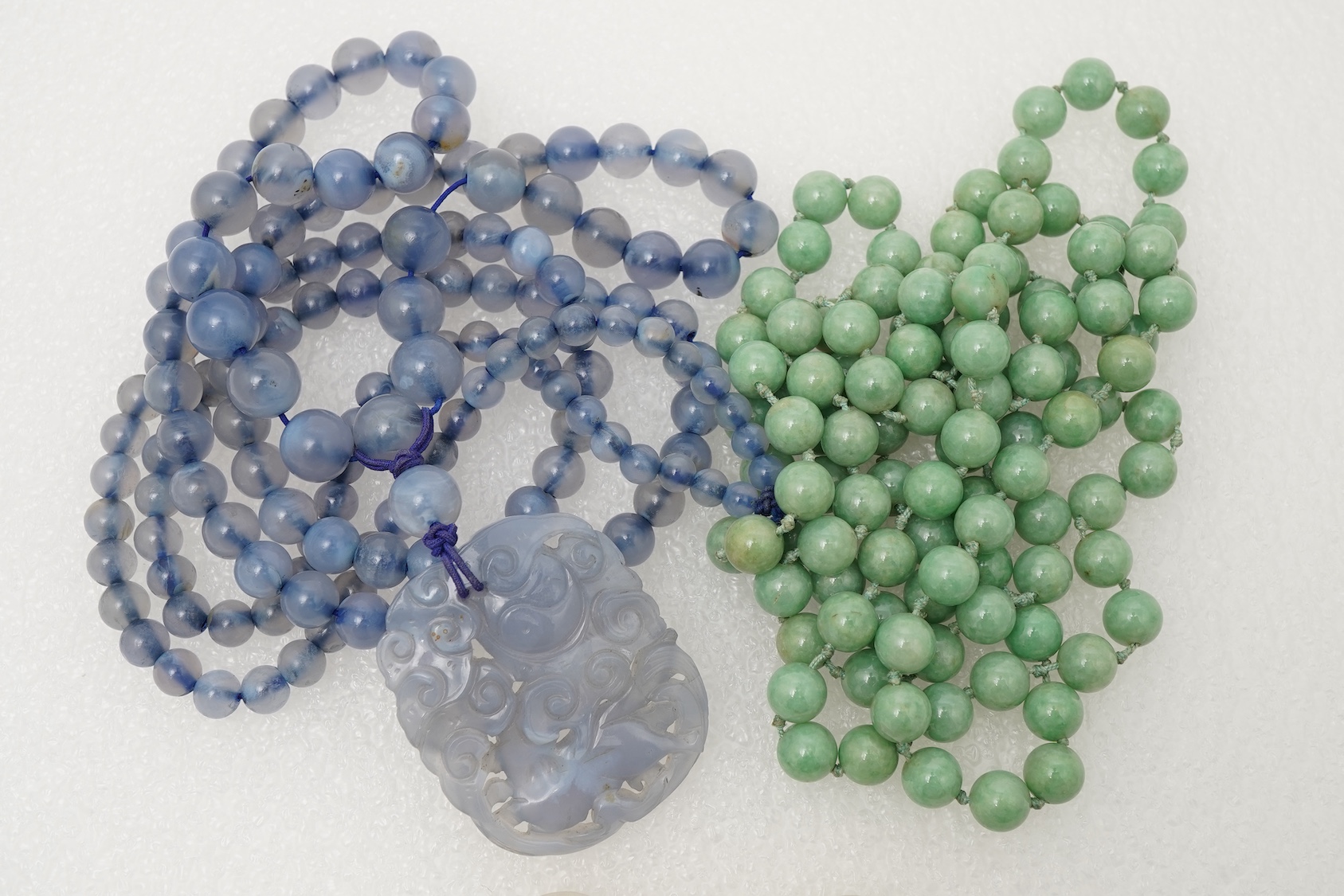 A Chinese jade ‘spirit lock’ plaque, a jadeite bead necklace and a blue quartz bead necklace, 20th century